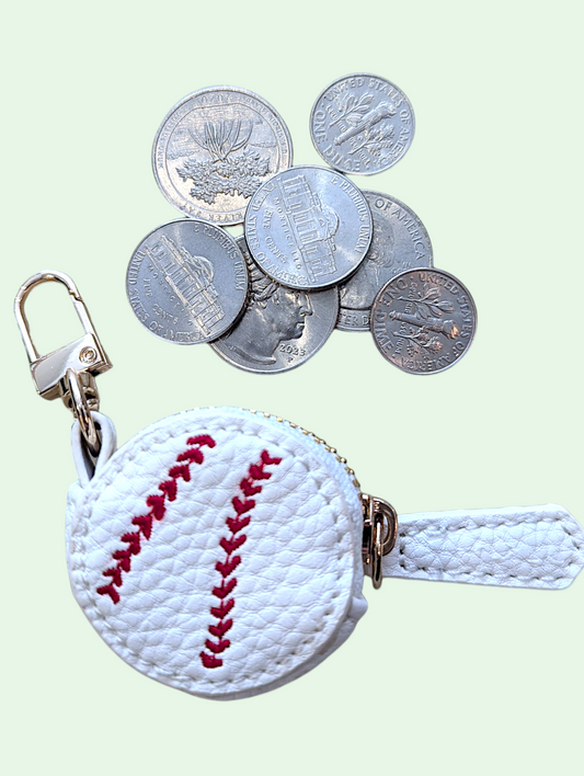 Baseball-shaped coin purse with coins on a light background