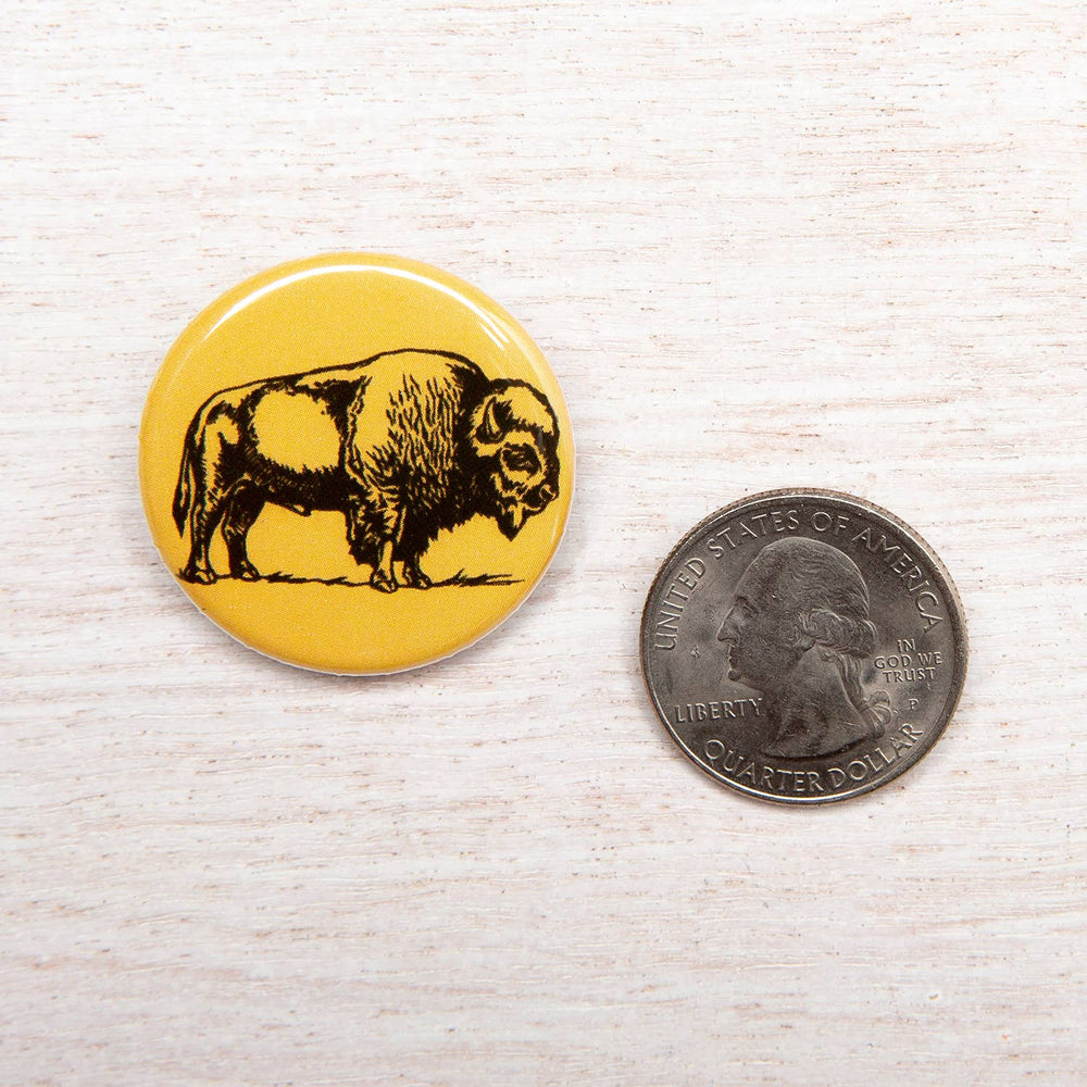 a size comparison shot of the bison button next to a quarter