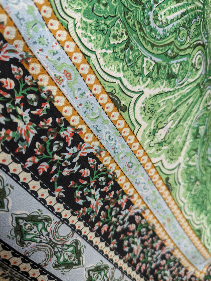 a close up of the fabric of the boho kimono, showing green and gold and black and red patterns