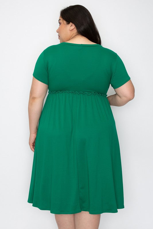 a dark haired model stands in a green dress with her back to the camera