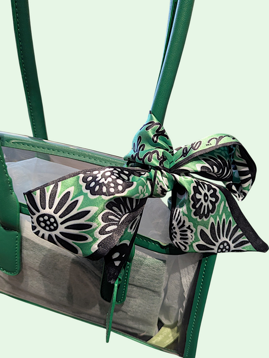 Green handbag with the scarf tied in a decorative bow on a light green background