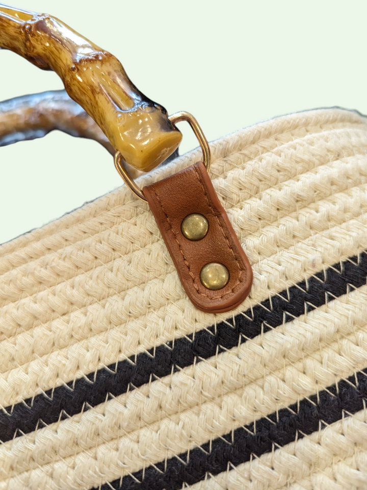 a detail shot of the straw bucket tote showing us the bamboo-look handle