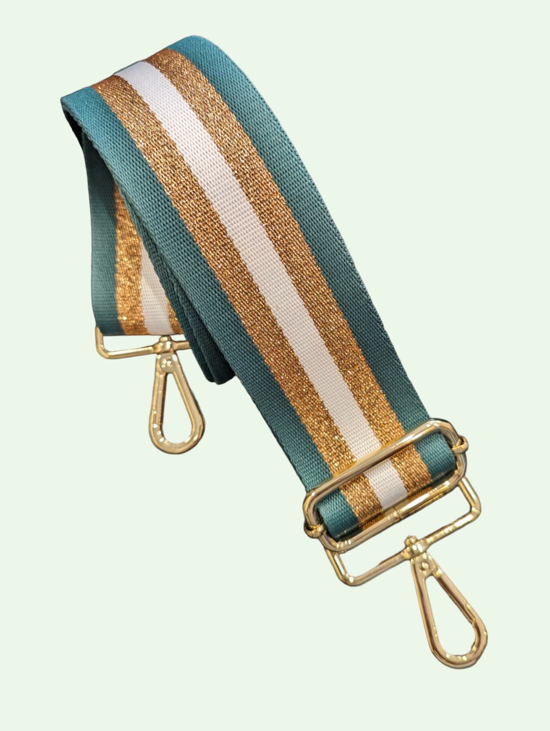 a studio shot of the woven interchangable bag strap showing the green webbing with gold stripes and gold hardware