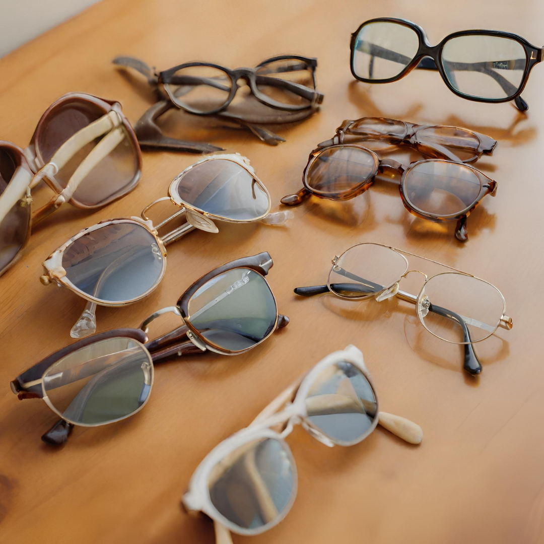 many different pairs of glasses on a wooden table