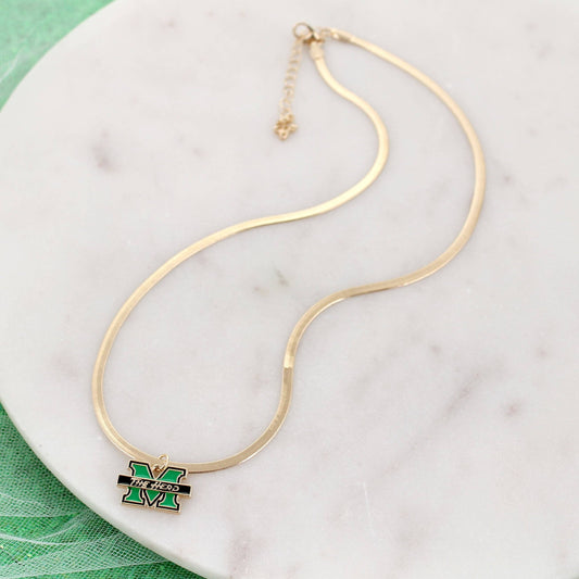 A gold-plated snake chain necklace featuring a Michigan State 'M' logo charm in green and black enamel, displayed on a white marble surface.