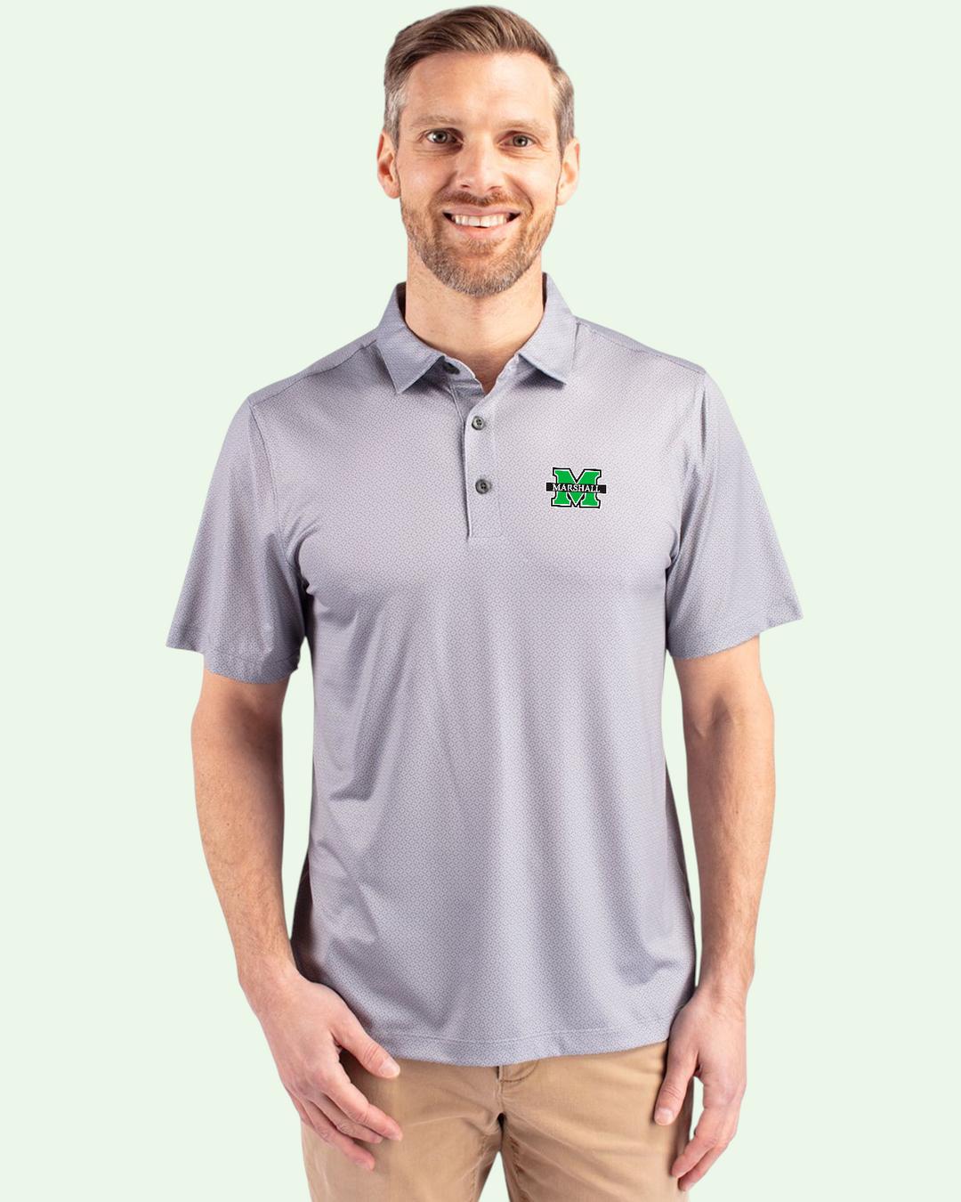 Man wearing a gray polo shirt with a logo on a light green background