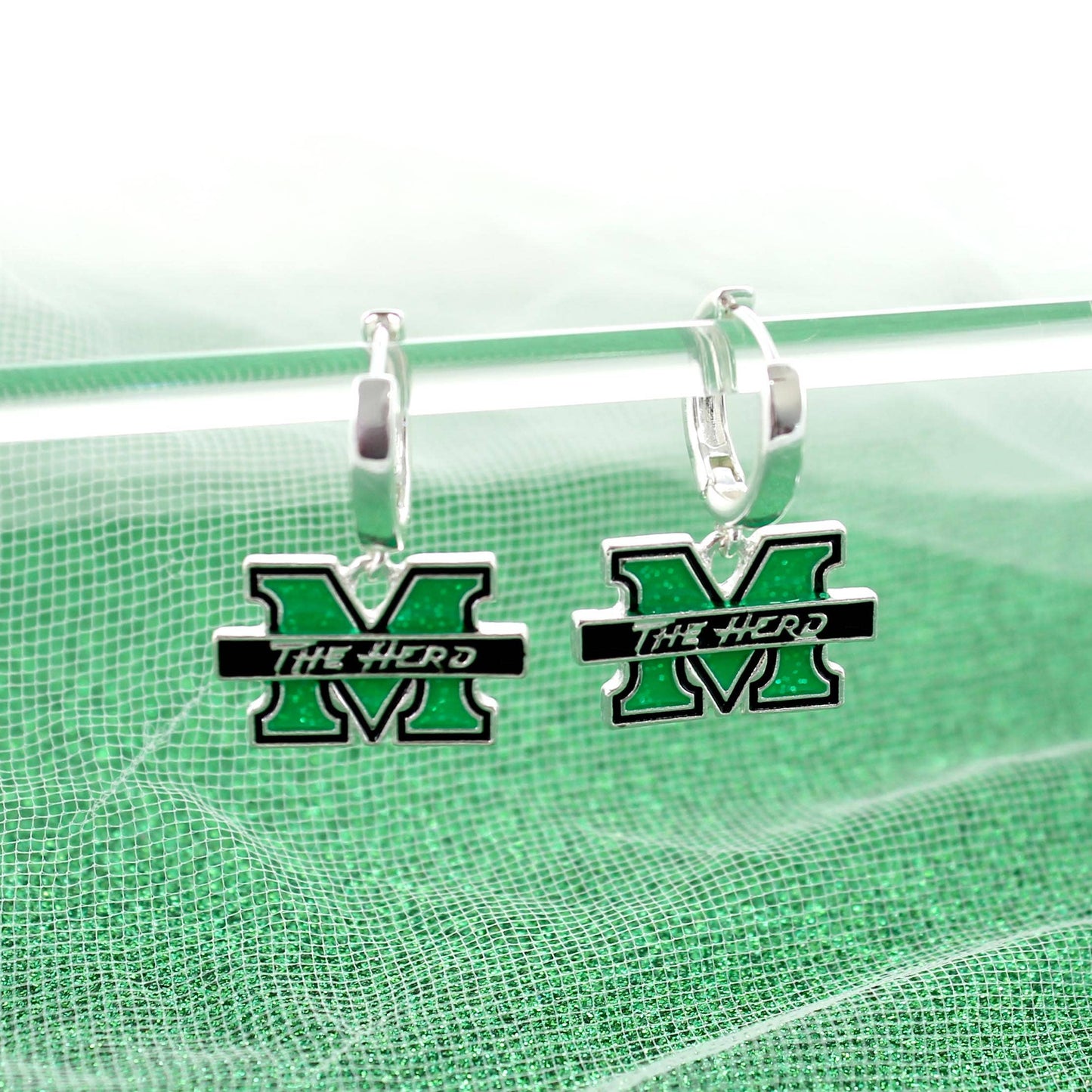 Green and silver earrings with 'The Herd' logo on a green background