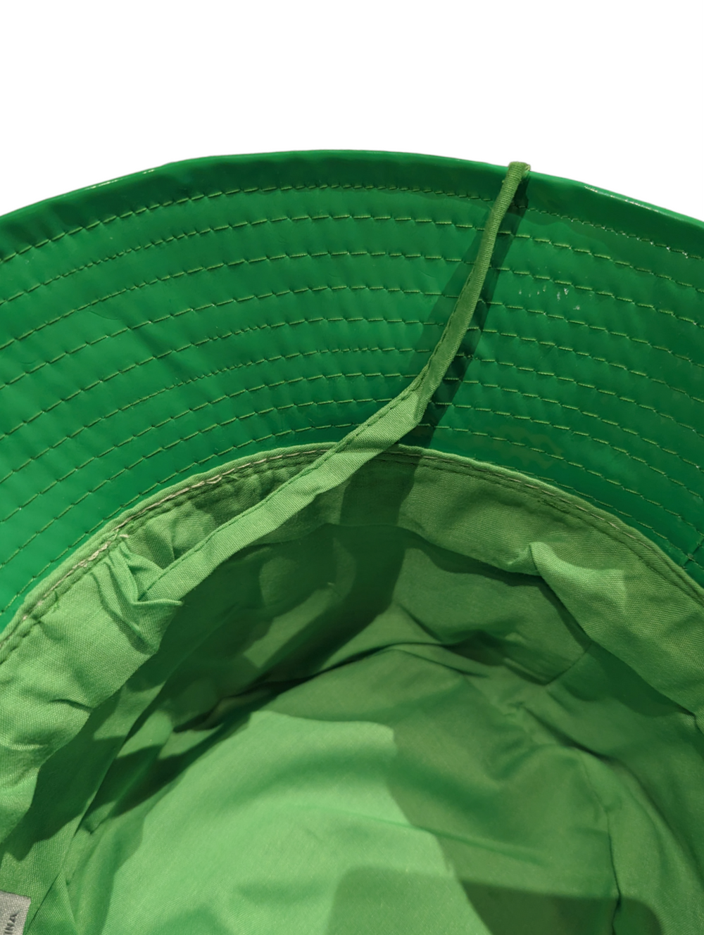 the underside view of the bucket hat showing a lighter green lining and an adjustable string