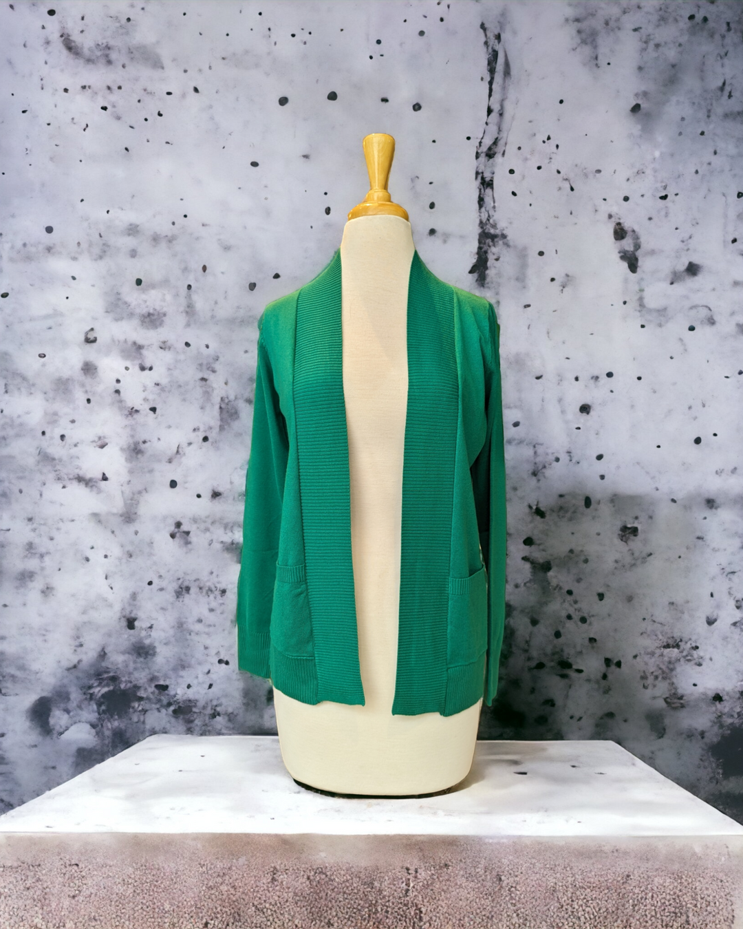 the green open front cardigan is shown on a mannequin in front of a concrete wall