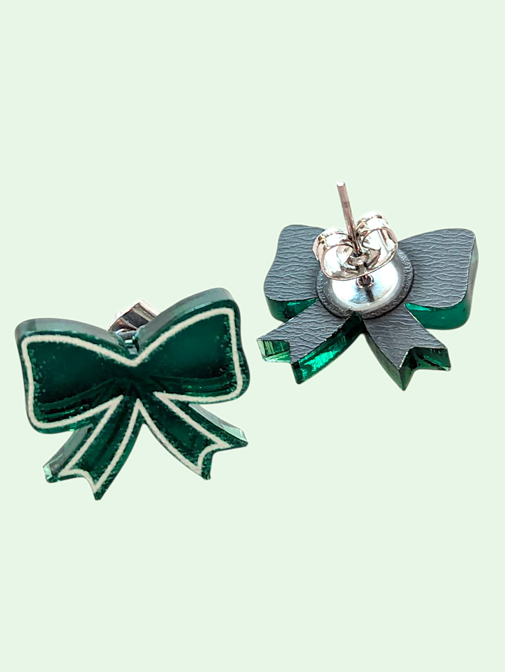 Green bow-shaped earrings on a light green background