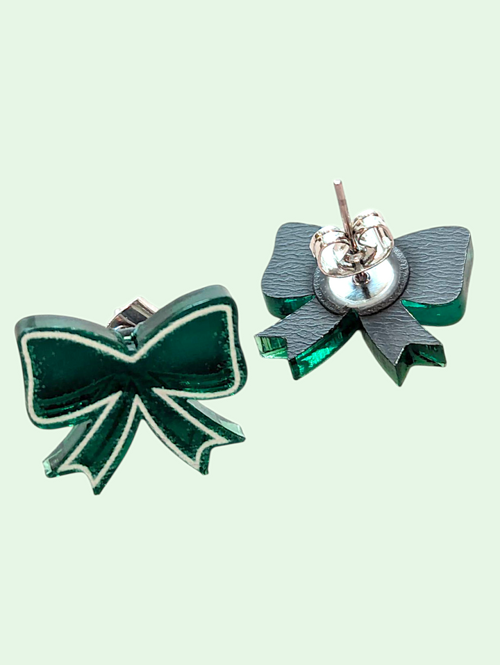 Green bow-shaped earrings on a light green background