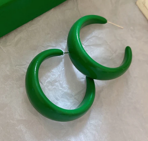 Green hoop earrings on a light gray surface