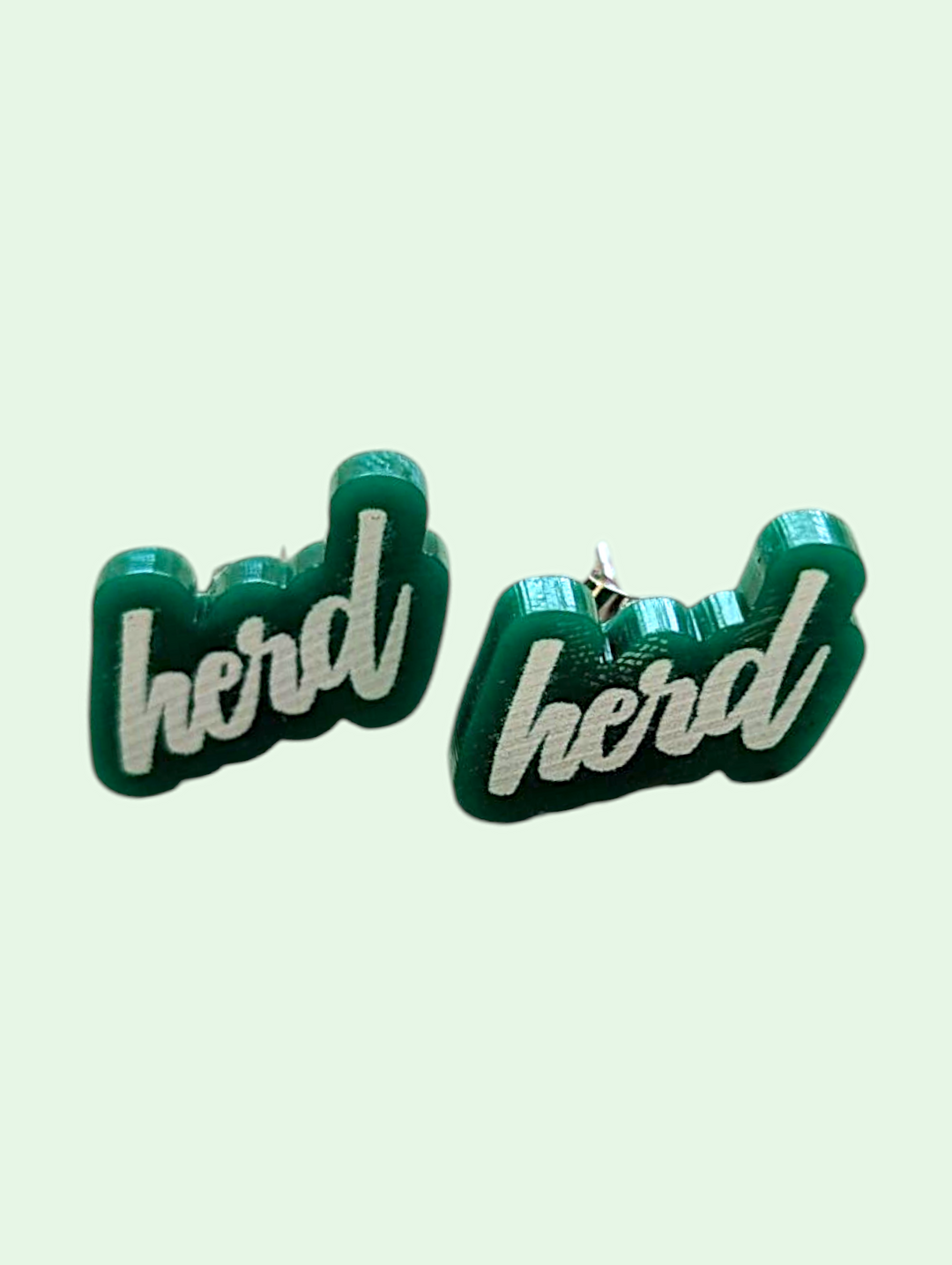 Green earrings with 'herd' text on a light green background