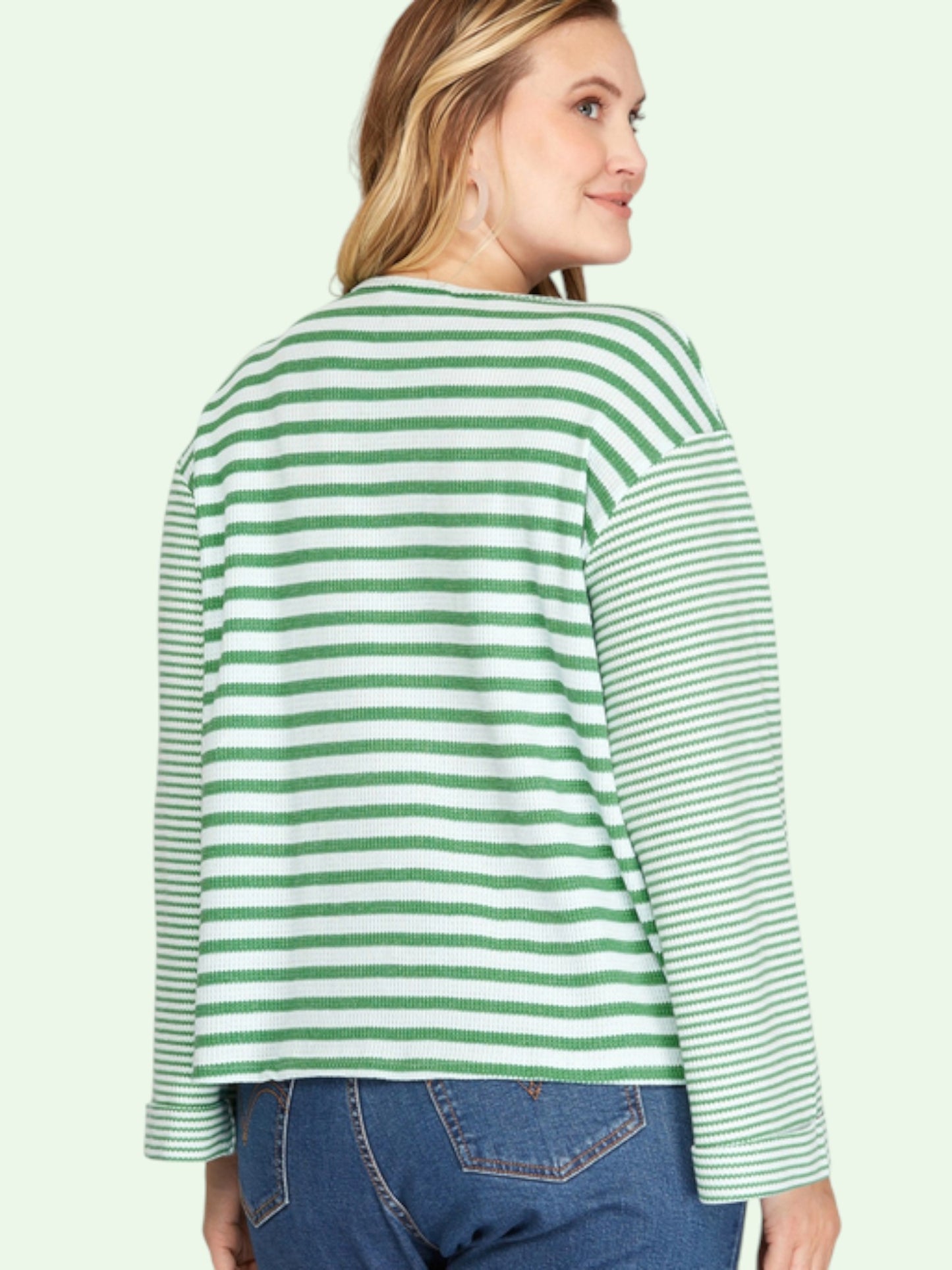 Woman wearing a green and white striped sweater on a light green background