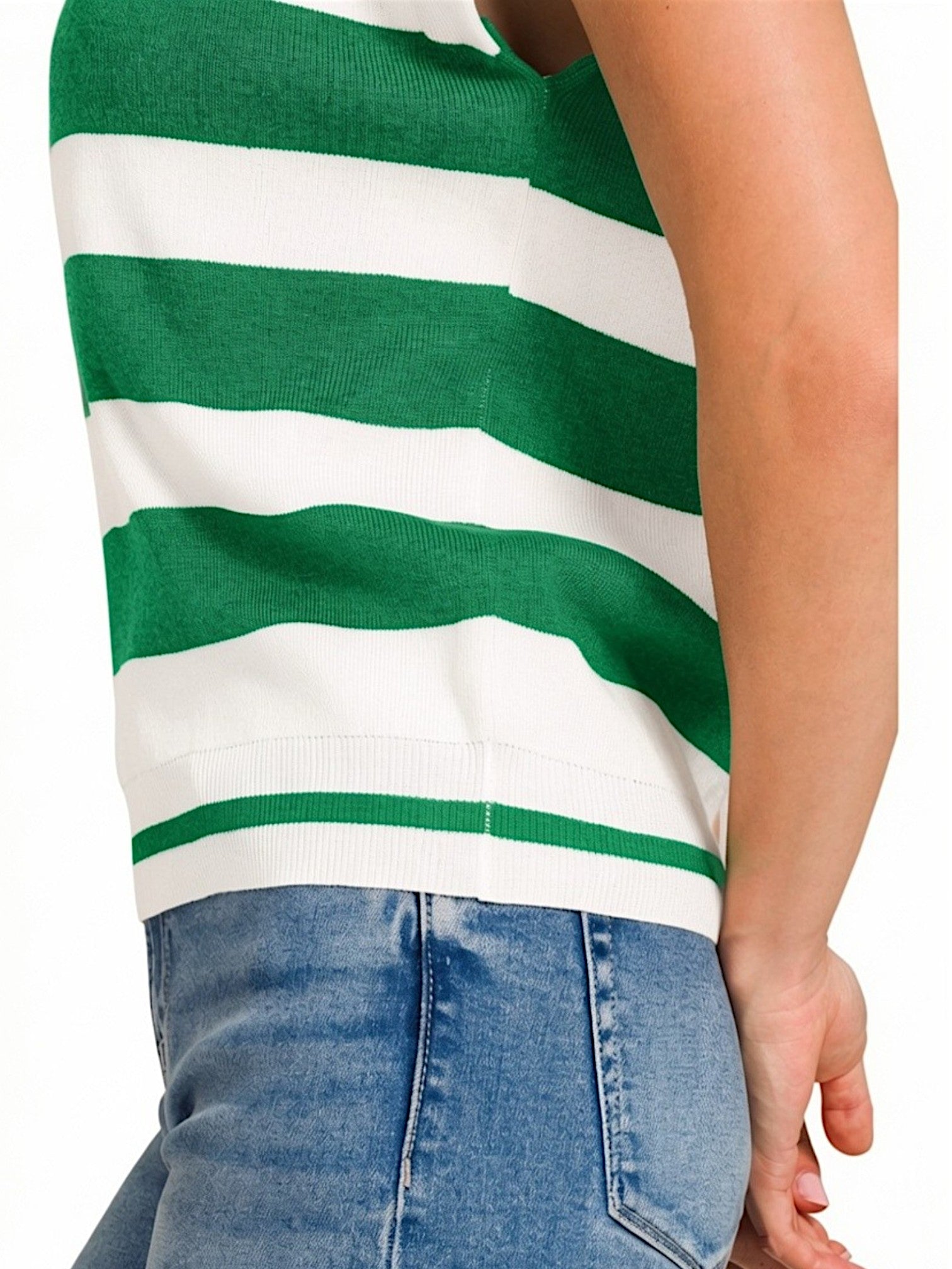 A close-up of a person wearing a green and white horizontally striped knit top with blue jeans, cropped from the chest down against a plain white background.