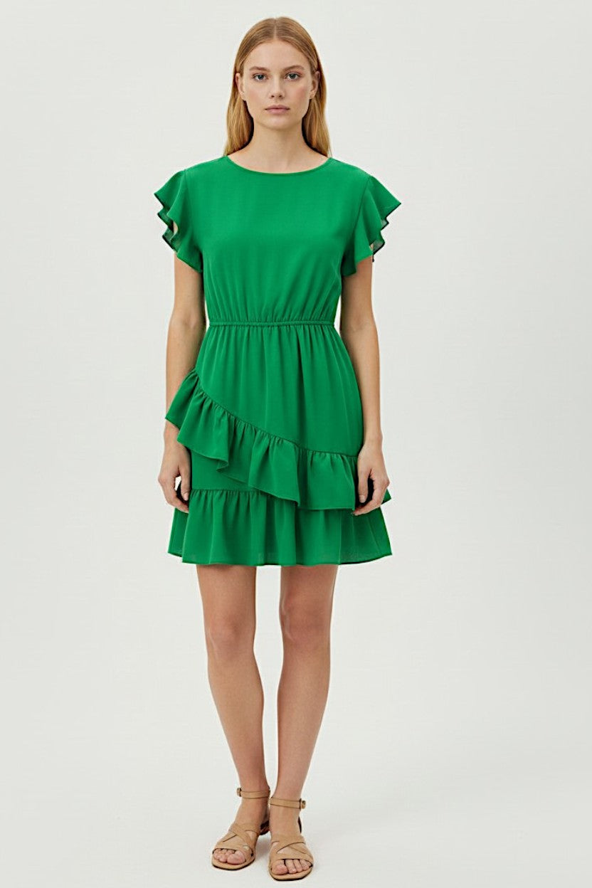 Woman wearing a green dress with ruffled sleeves and layered skirt on a white background