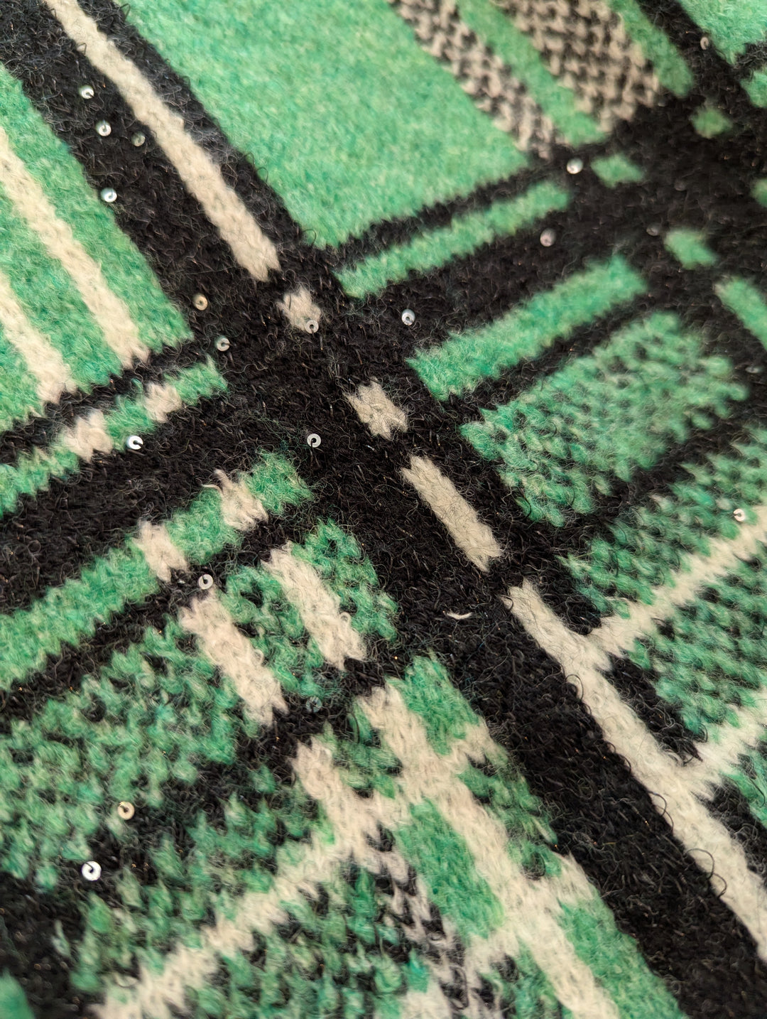 Close-up of a green, black, and white checkered pattern fabric showing attached sequins