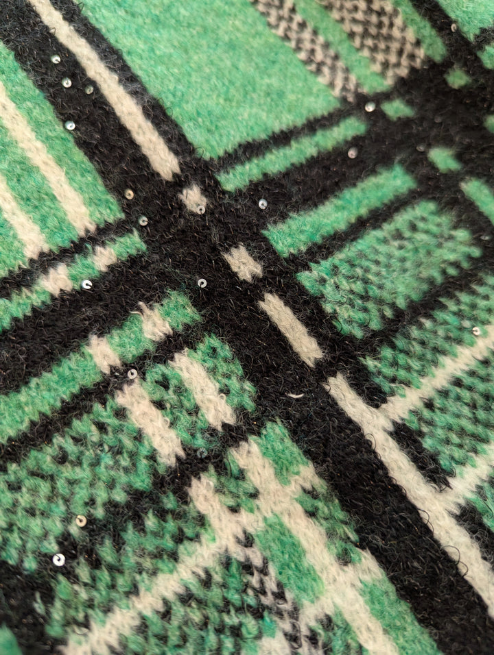 Close-up of a green, black, and white checkered pattern fabric showing attached sequins