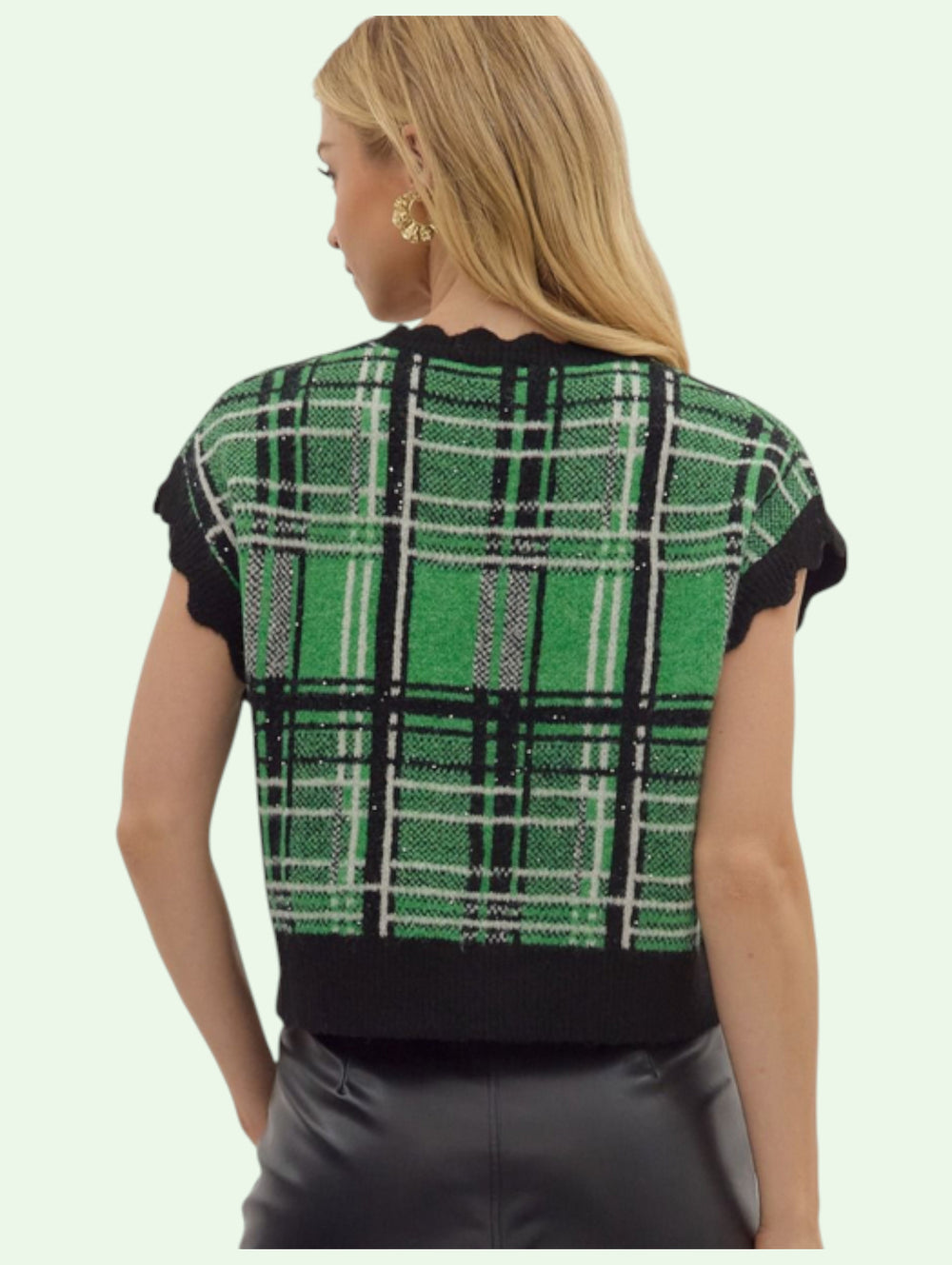 the back of a green and black plaid vest worn by a person on a light green background