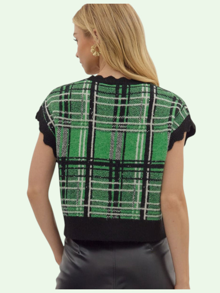the back of a green and black plaid vest worn by a person on a light green background