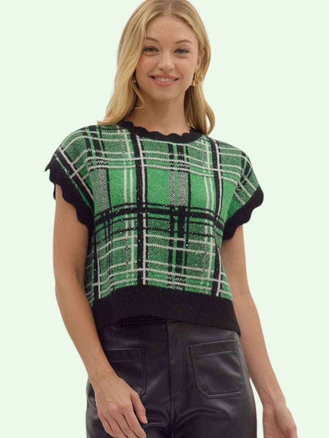 Woman wearing a green and black plaid top with a plain background