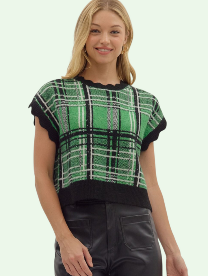 Woman wearing a green and black plaid top with a plain background