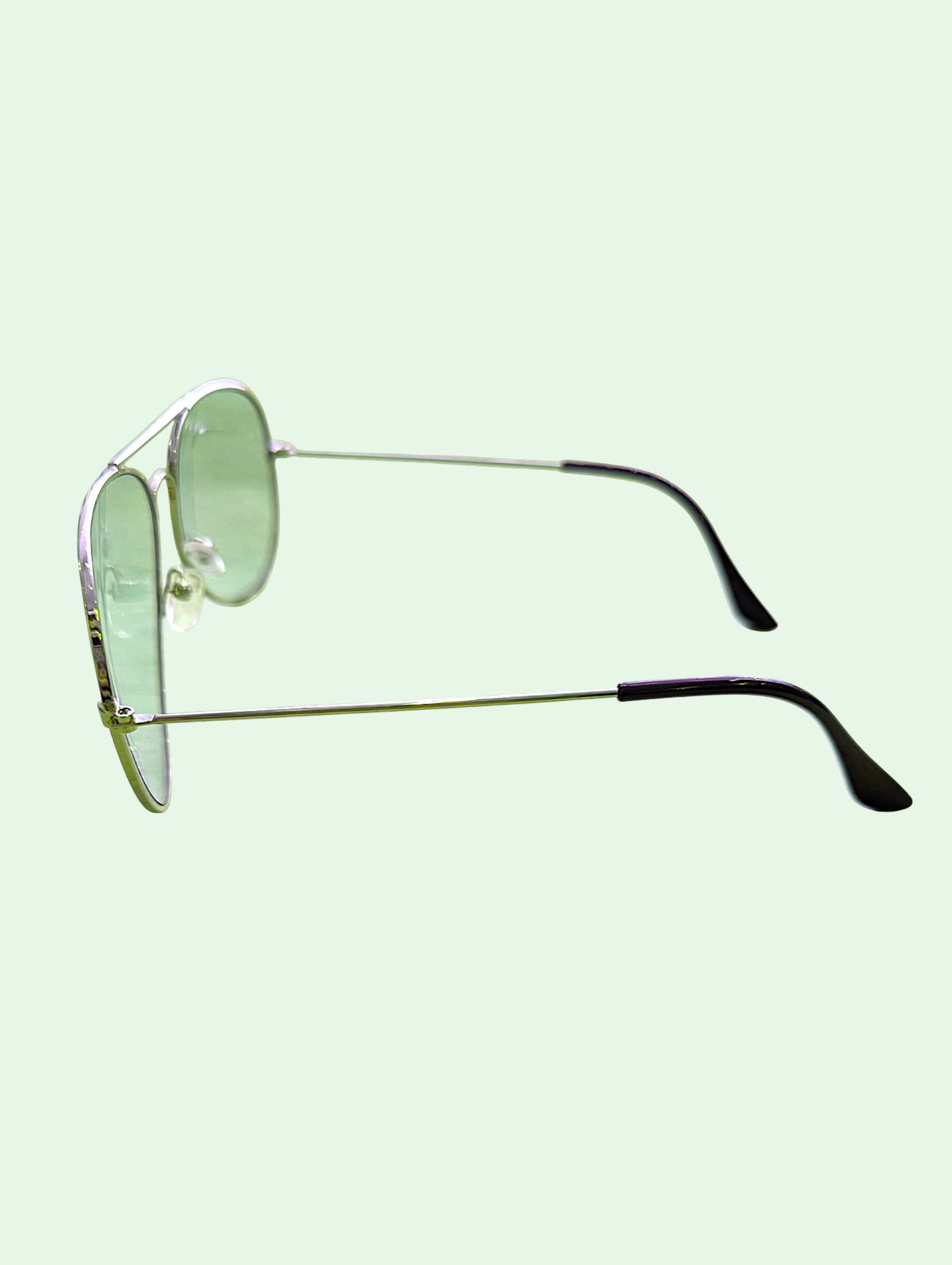 Sunglasses with green lenses and metal frames on a light green background