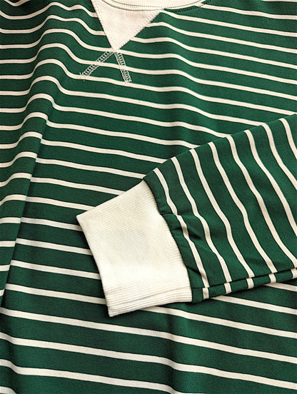 A close-up of a green and white striped long-sleeve henley shirt, showing the striped fabric and a ribbed white collar and sleeve cuff.