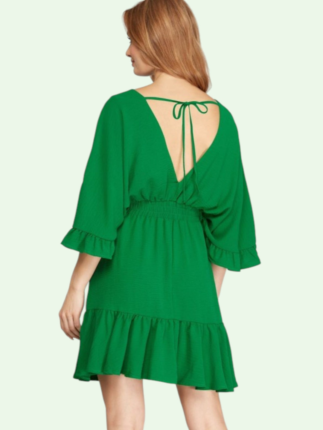 Green dress with ruffled sleeves and hem on a white background