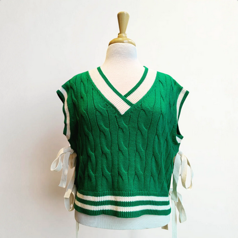 Green sweater vest with white trim on a mannequin against a white background