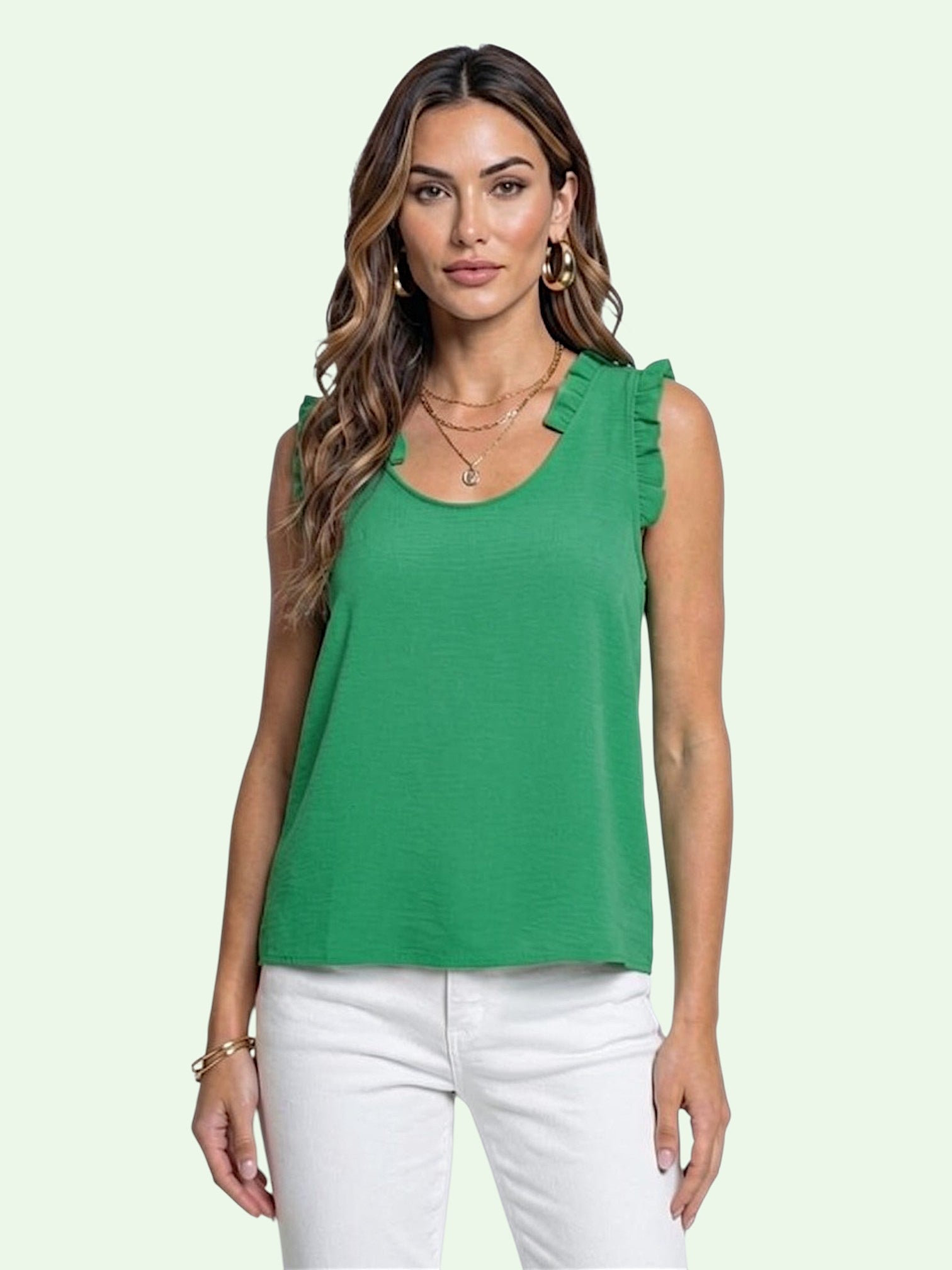 Woman wearing a green sleeveless top with ruffled shoulders on a light green background