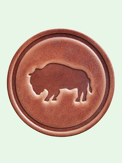 Brown circular object with a silhouette of a buffalo on a light green background