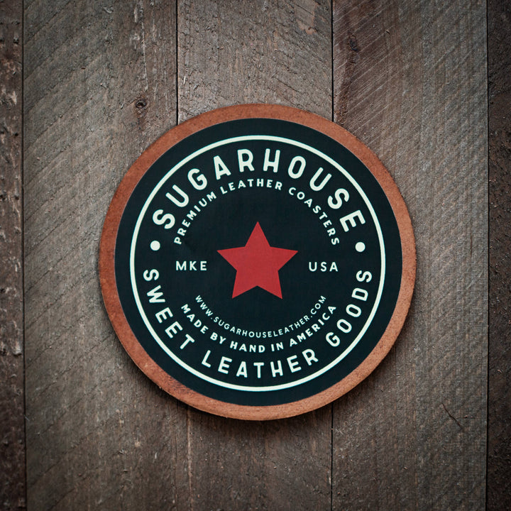 Round leather coaster with 'Sugarhouse Premium Leather Coasters' branding on a wooden background