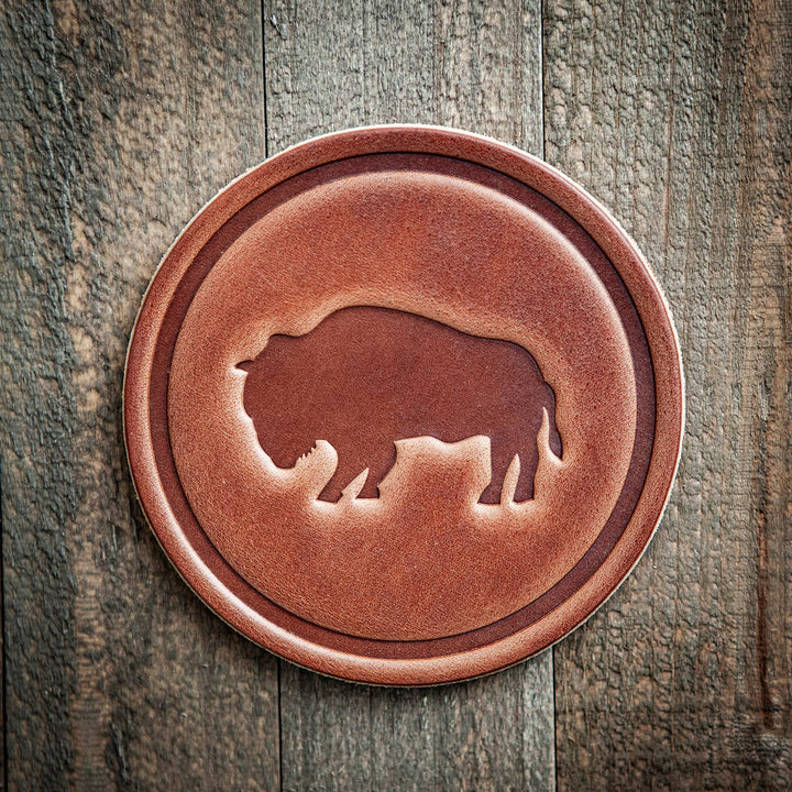 Round leather coaster with a bear design on a wooden surface