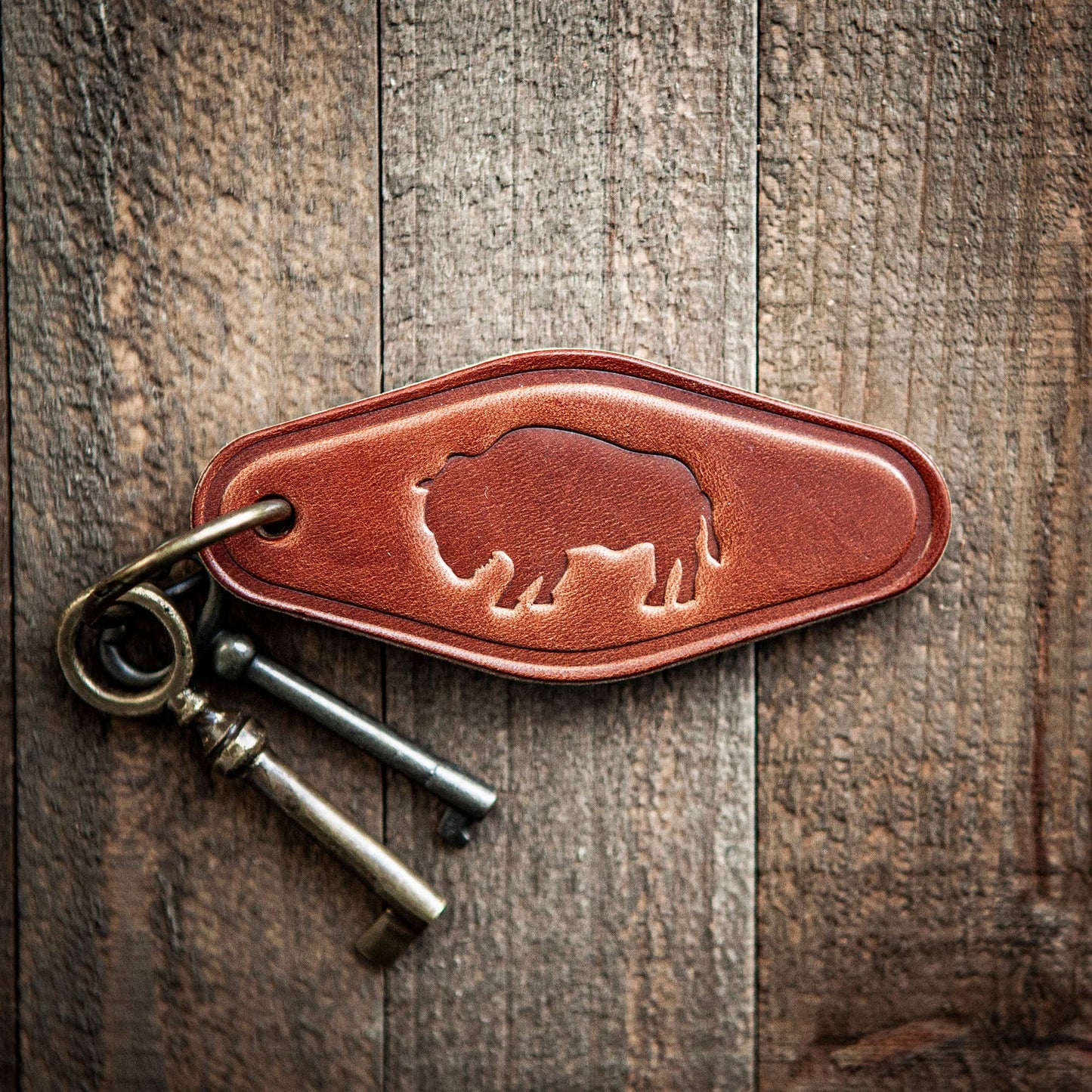 Brown leather key fob with a bear design on a wooden surface