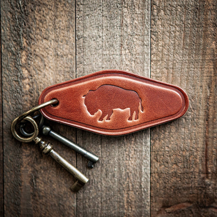 Brown leather key fob with a bear design on a wooden surface