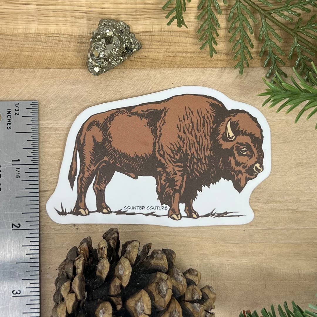 Bison sticker on a wooden surface with a ruler for scale