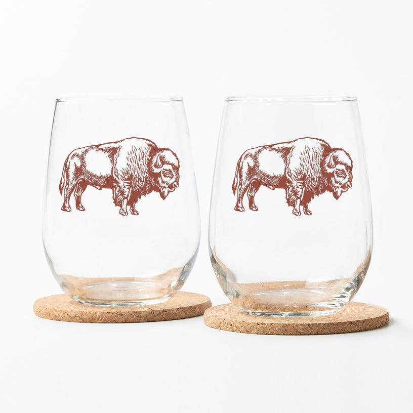 Two stemless wine glasses with bison illustrations on cork bases.