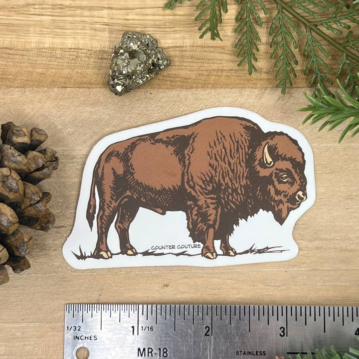 Bison sticker on a wooden surface with a ruler for scale