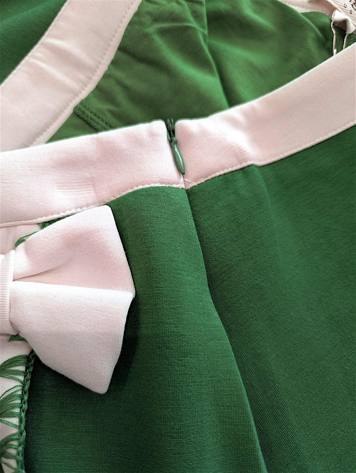 Close-up of a green skort with white trim and a bow detail.