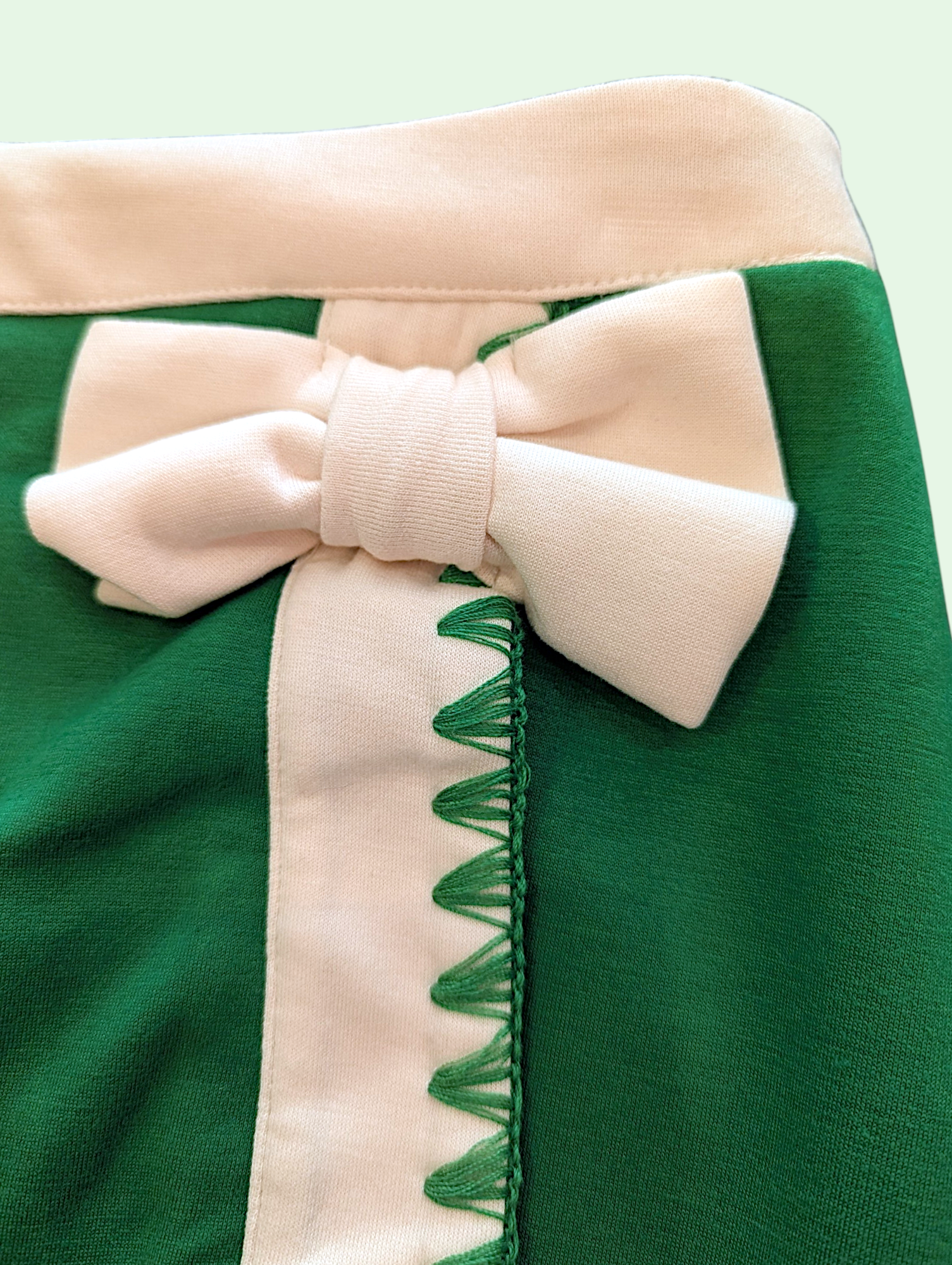 Close-up of a green skort with a white bow on a light green background