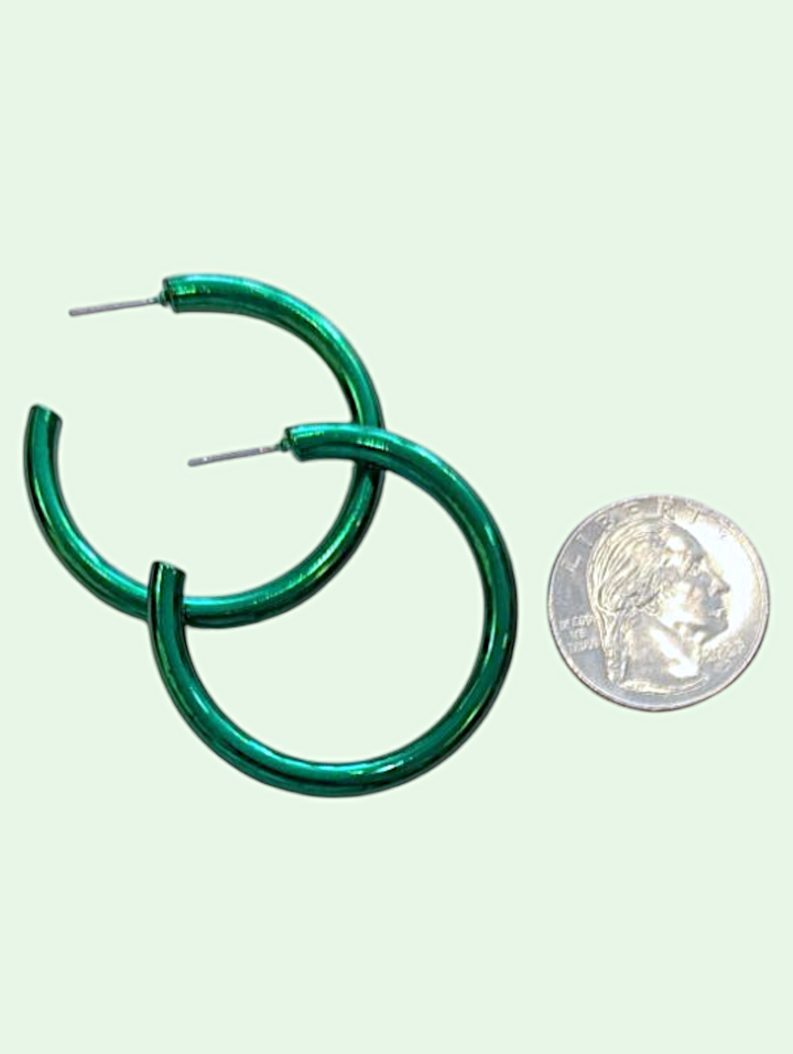 Green hoop earrings next to a silver coin on a light green background