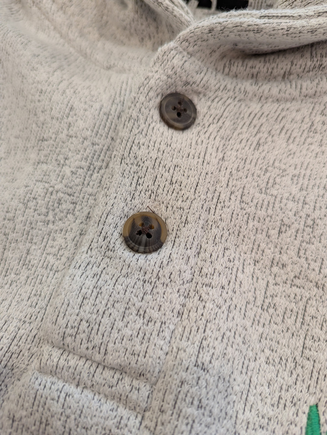 Close-up of a textured beige fabric with buttons on a garment.