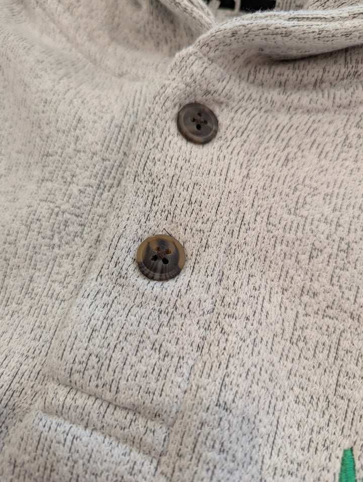Close-up of a textured beige fabric with buttons on a garment.