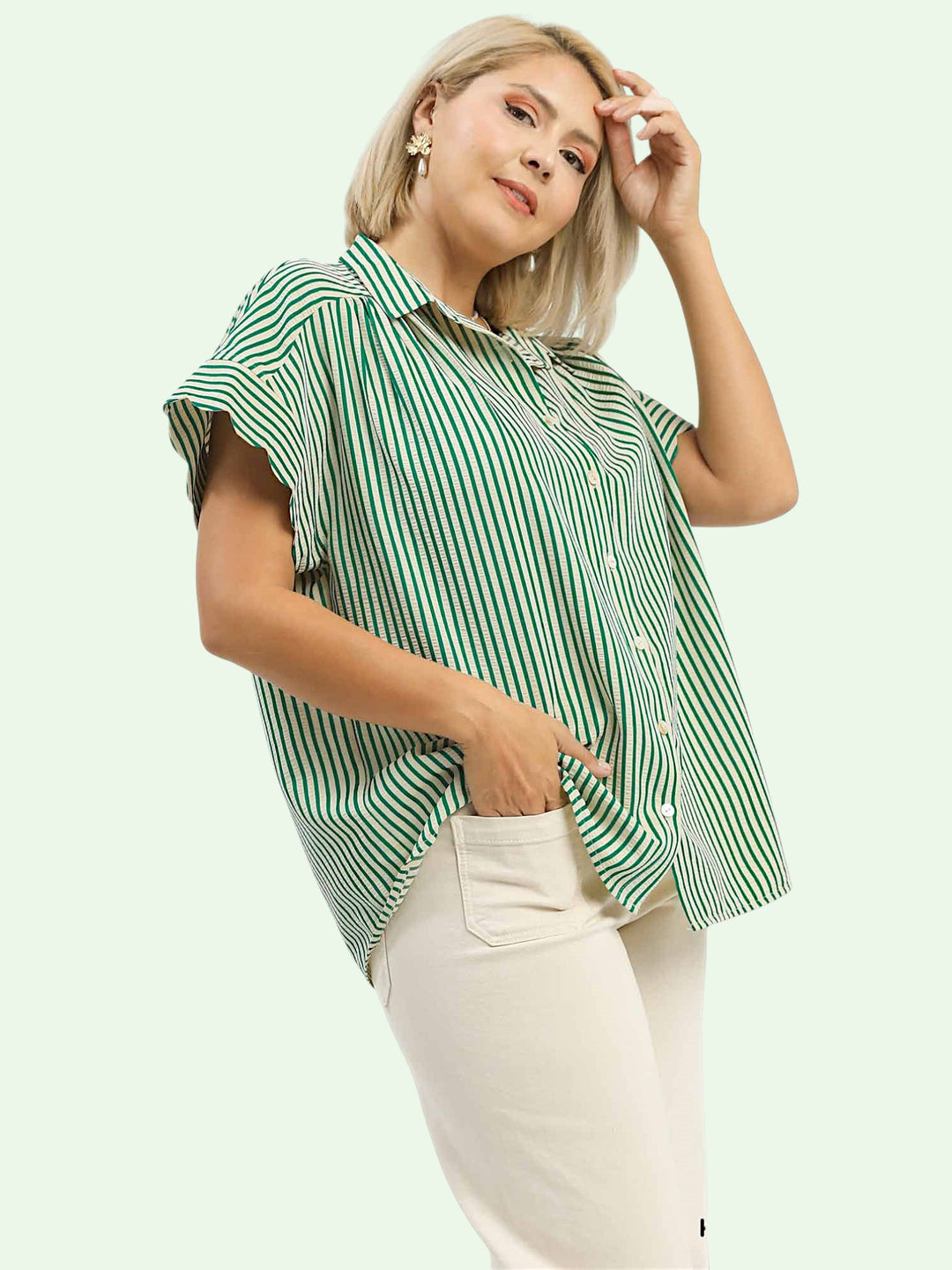 Woman wearing a green and white striped shirt with beige pants on a light green background