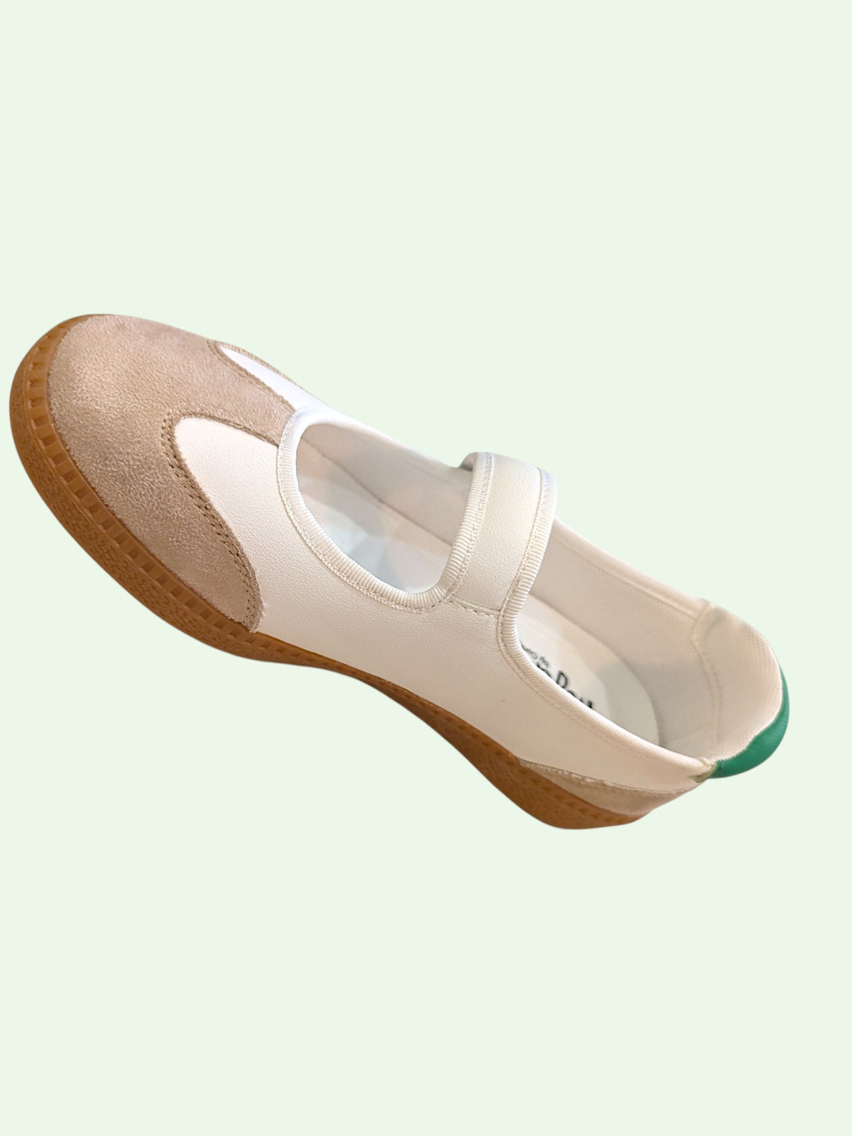 White shoe with brown sole on a light green background