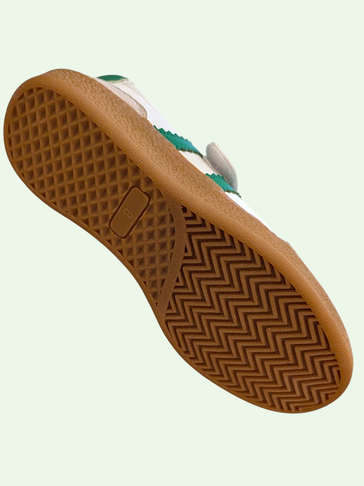 Close-up of a brown shoe sole with a textured pattern on a light green background