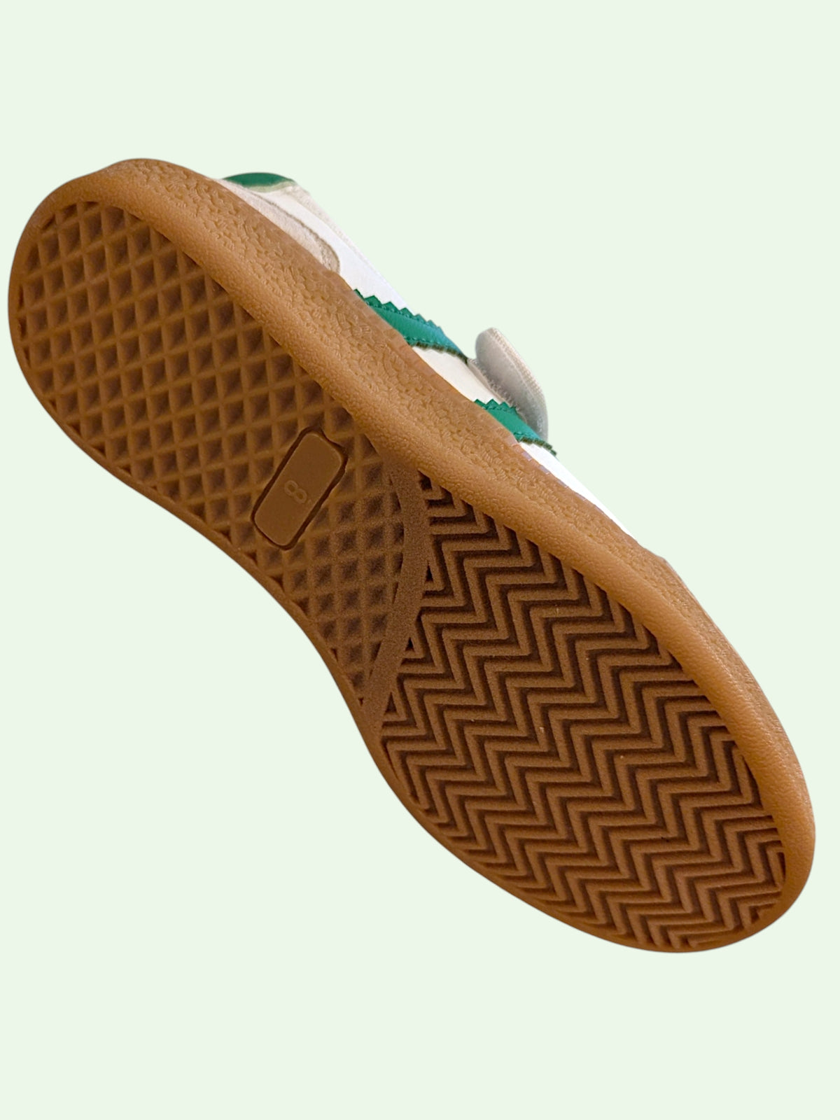 Close-up of a brown shoe sole with a textured pattern on a light green background