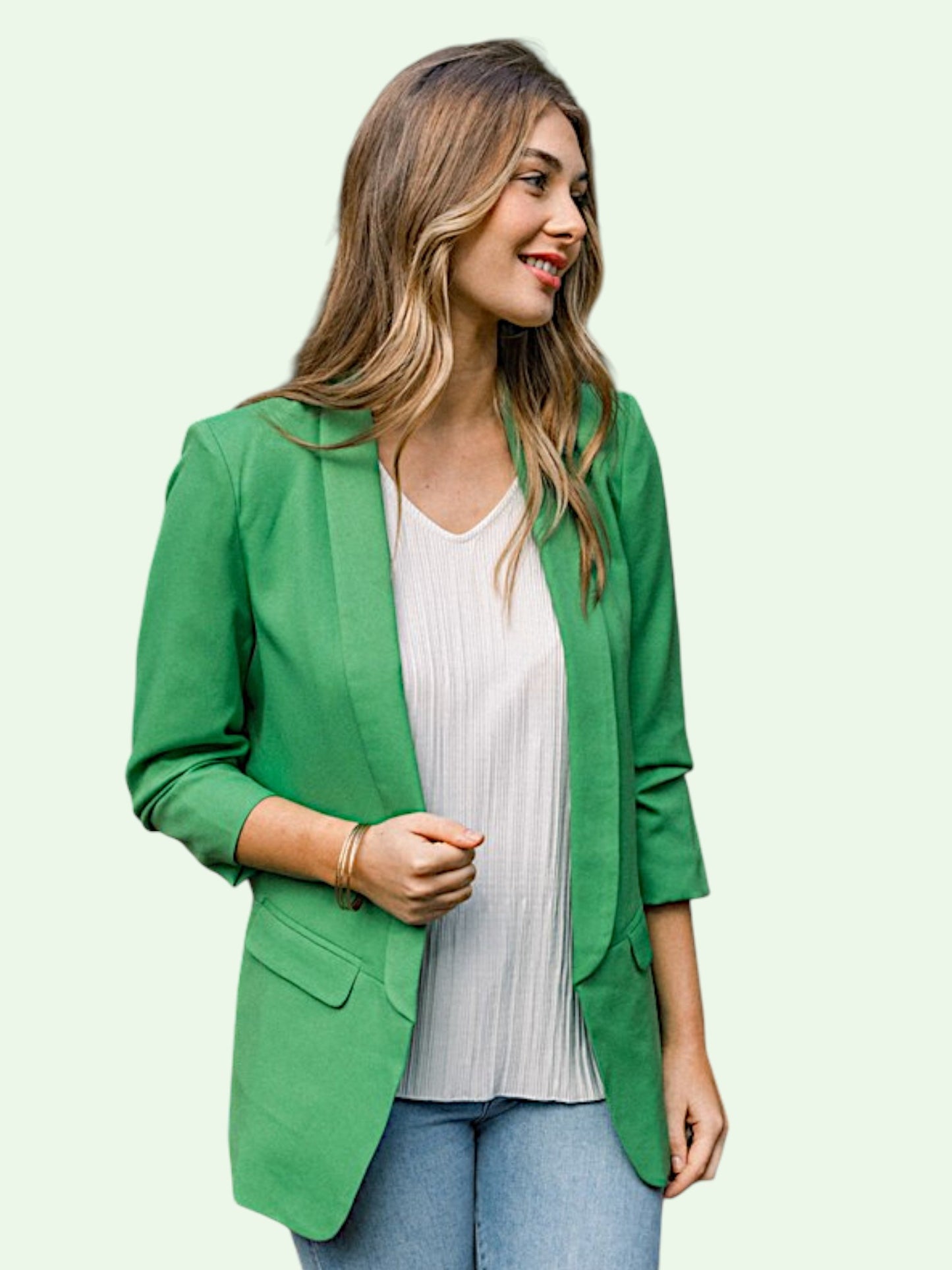 Woman wearing a green blazer over a white top on a light background