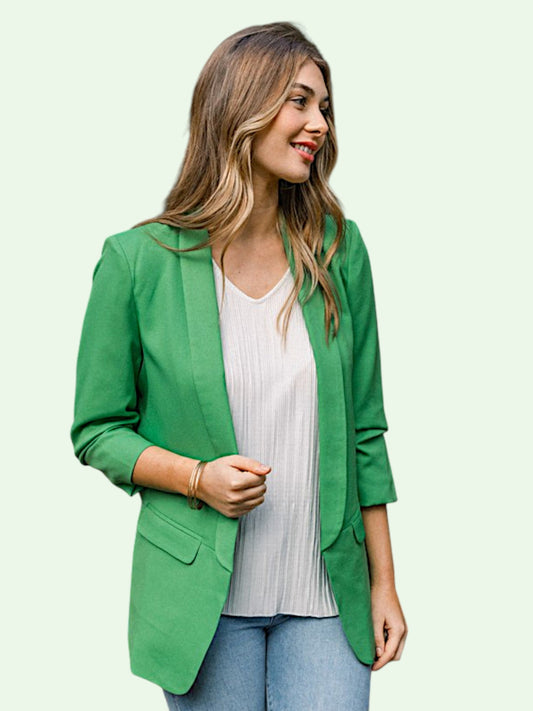 Woman wearing a green blazer over a white top on a light background